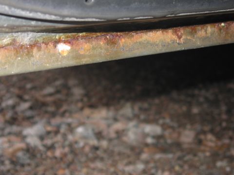 2001 Ford Crown Victoria - Detail of a rusted rocker panel on a 2001 Ford Crown Victoria, indicating potential corrosion issues.