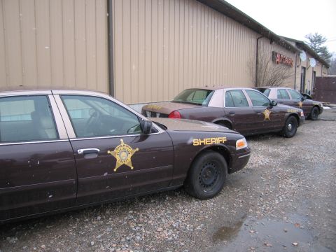 2001 Ford Crown Victoria - Three sheriff department Ford Crown Victoria patrol cars are lined up outside a building.