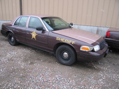 2001 Ford Crown Victoria - A sheriff's car is parked outside a building. Another sheriff's car is visible to the right.