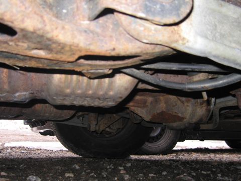 2001 Ford Crown Victoria - The undercarriage of a vehicle displays significant rust on its frame and exhaust components.