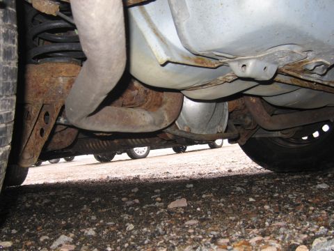 2001 Ford Crown Victoria - The undercarriage of a vehicle displays significant rust on its exhaust system and suspension components.