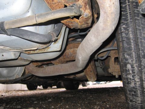 2001 Ford Crown Victoria - The underside of a vehicle reveals significant rust and corrosion on its exhaust system and frame components.