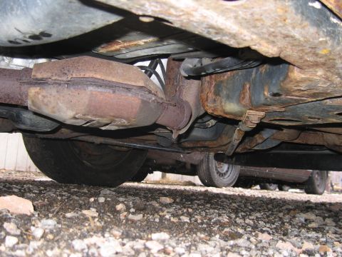 2001 Ford Crown Victoria - The undercarriage of a vehicle, revealing significant rust on the exhaust system and frame components.