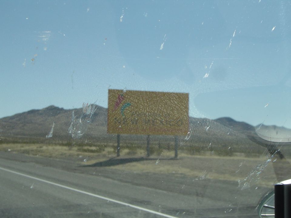 Blank yellow billboard beside a desert highway seen through a windshield