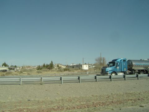 1989 Ford Bronco - A blue semi-truck travels down a highway next to a guardrail with a tanker trailer attached.