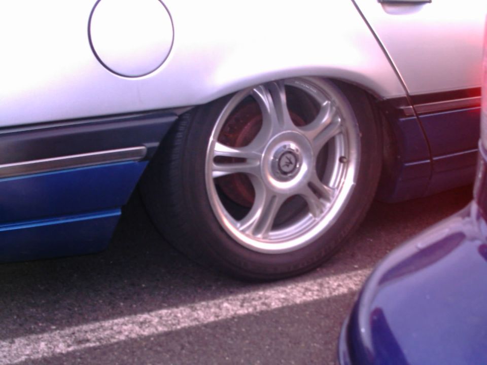 Lowered silver sedan rear wheel with silver aftermarket rims and low-profile tire