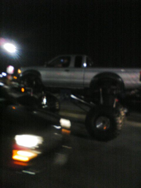 2001 Nissan Frontier - A lifted silver pickup truck is visible at night, with another vehicle in the foreground.
