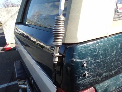 1995 Ford Bronco - A close-up shot of a CB antenna mount on the rear of a vehicle, showing wear and tear on the paint.