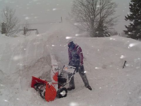 2000 Chevrolet Tahoe - A person operates a snow blower in heavy snowfall, clearing a path through deep snow.