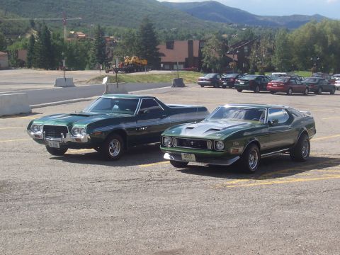 1973 Ford Mustang - Two green classic American cars, a Mustang Mach 1 and a Ranchero, are parked in an outdoor lot.
