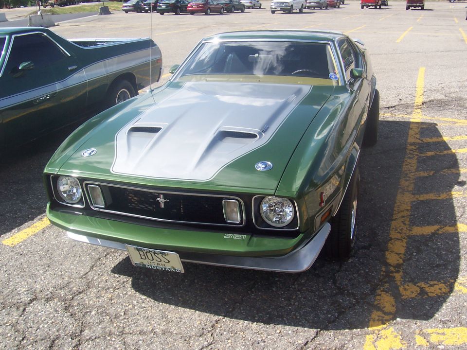 Green 1973 Ford Mustang Boss 351 parked next to a green pickup truck