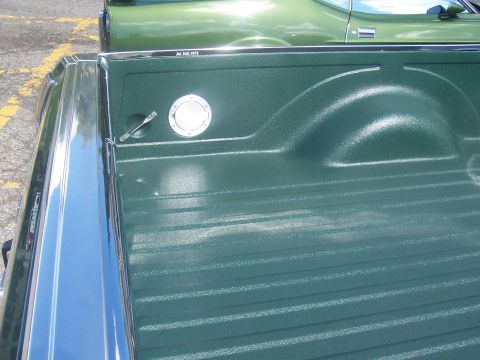 1972 Ford Ranchero - The bed of a 1972 Ford Ranchero shows its textured green finish, chrome rail, and a circular fuel filler cap with 'Jet fuel only' text.