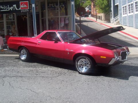 1972 Ford Ranchero - A red 1972 Ford Ranchero is parked on a street with its hood open, in front of a Quiksilver store.