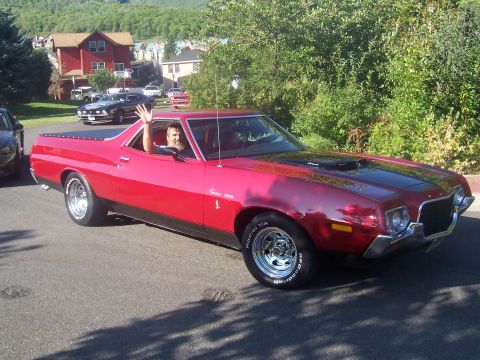 1973 Ford Mustang - A red 1973 Ford Ranchero is seen driving down a street with a driver waving.