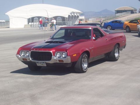 1973 Ford Mustang - A red 1972 Ford Ranchero is parked at an outdoor event with other vehicles and people visible.