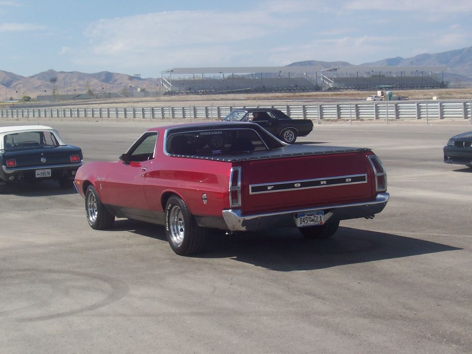 Red 1970 Ford Ranchero with a black tonneau cover, seen from the rear