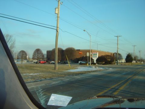 1992 Ford Bronco - A daytime scene shows a street with a building and several vehicles parked nearby. Snow is visible on the ground.