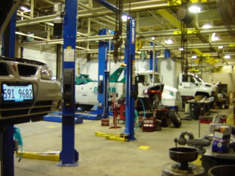 1992 Ford Bronco - Interior view of an auto repair shop with multiple vehicles on lifts and in bays.