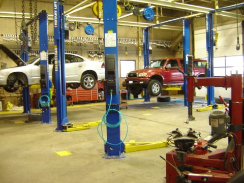 1992 Ford Bronco - Auto repair shop scene with a white sedan and a red SUV on lifts.