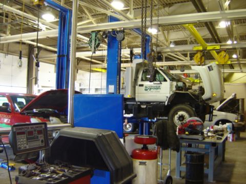 1992 Ford Bronco - A garage scene with a service truck and another vehicle on lifts, surrounded by tools and equipment.