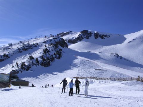 1983 Ferrari Enzo - Ski resort scene with skiers on a slope under a clear blue sky.