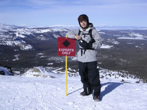 1983 Ferrari Enzo - A skier stands by a sign indicating 'Experts Only' on a snow-covered mountain slope, with a vast landscape in the background.