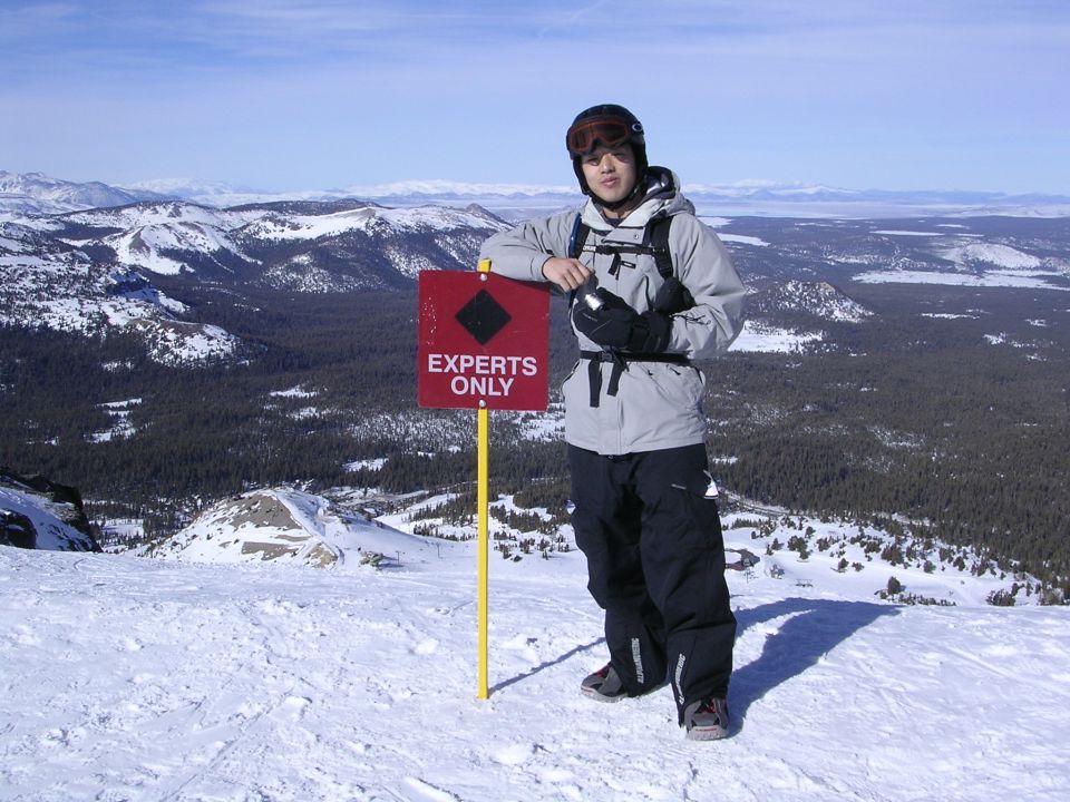 Skier by 'Experts Only' sign on snowy mountain