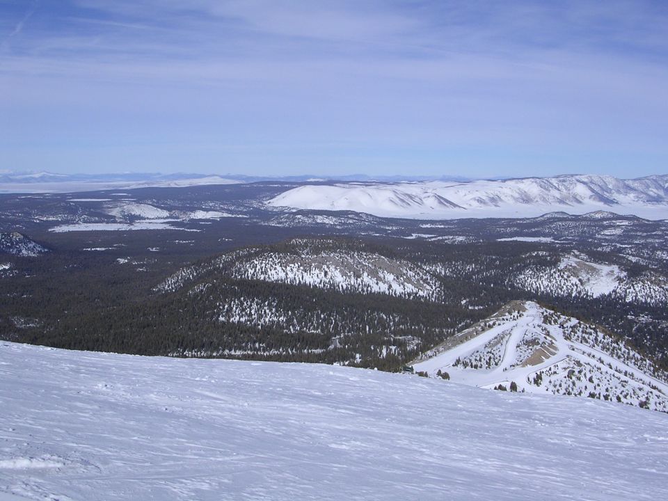 Snowy mountain landscape with trees and a blue sky. Text 'SUPERMOTORS' is visible