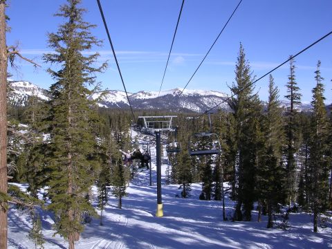1983 Ferrari Enzo - A ski resort scene with chairlifts moving up a mountain, surrounded by pine trees and snow-covered terrain.