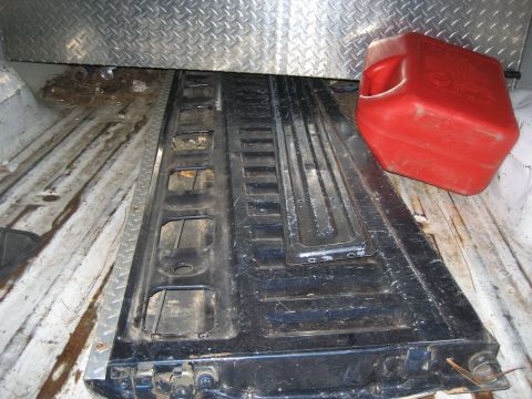 1981 Ford Bronco - The interior of a truck bed shows a diamond plate lining and a red gas can.