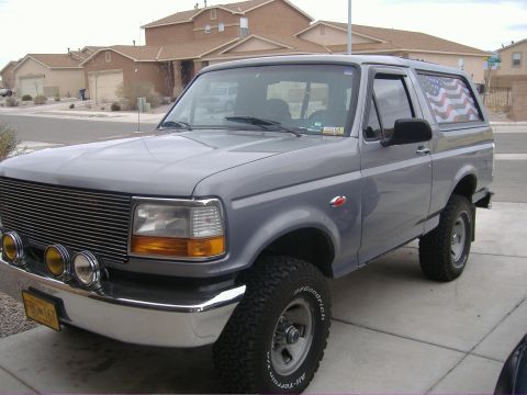 1995 Ford Bronco - This gray Ford Bronco is parked in a suburban driveway with houses in the background.