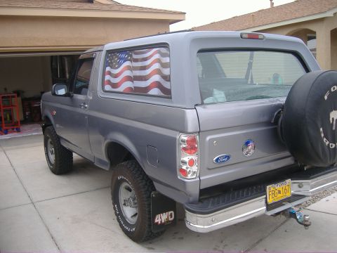 1995 Ford Bronco - This 1995 Ford Bronco is shown from the rear quarter with a spare tire mounted and an American flag decal in the window.