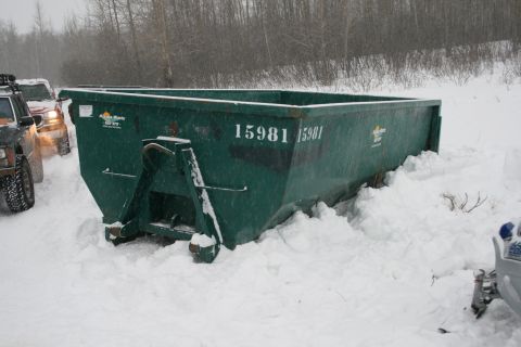 2003 Jeep TJ - Two vehicles are partially visible next to a large green dumpster in a snowy outdoor scene.