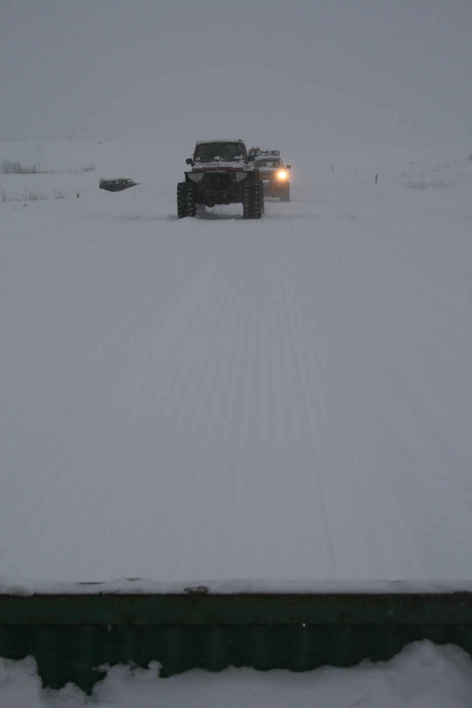 Front view of two off-road vehicles with large tires driving on a snow-covered path