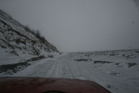 2003 Jeep TJ - A person walks on a snowy dirt road beside a snow-covered hill.