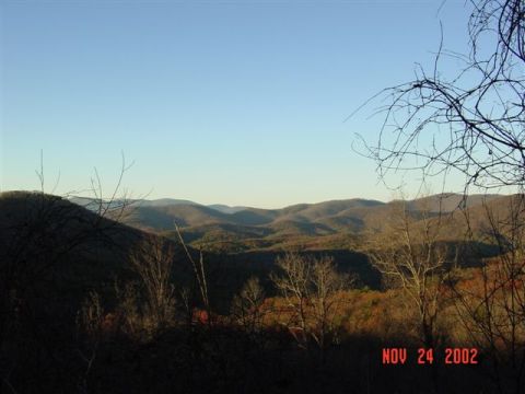 1995 Ford Bronco - Scenic overlook of rolling forested Appalachian ridgelines in late-autumn color, framed by bare tree branches under a clear blue sky, with…