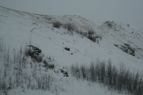 2003 Jeep TJ - A winter scene of a snow-covered hillside with sparse vegetation and some debris scattered across the landscape.