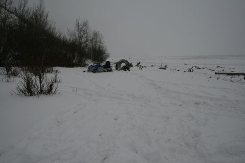 2003 Jeep TJ - Snowmobile and discarded tires sit in a snowy landscape with trees in the background.