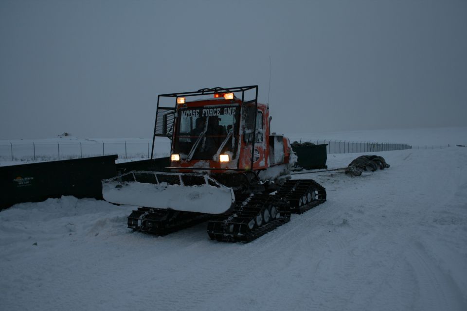 Orange snow groomer with "MOOSE FORCE ONE" text in a snowy landscape