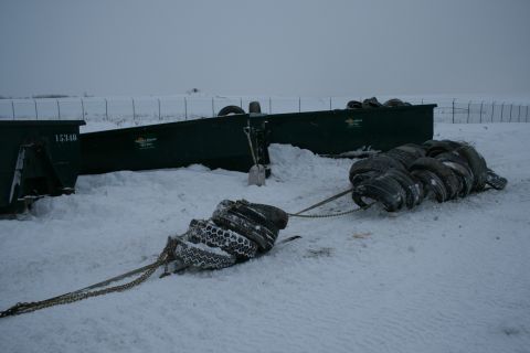 2003 Jeep TJ - Two large green dumpsters sit in the snow next to a chain of tires.