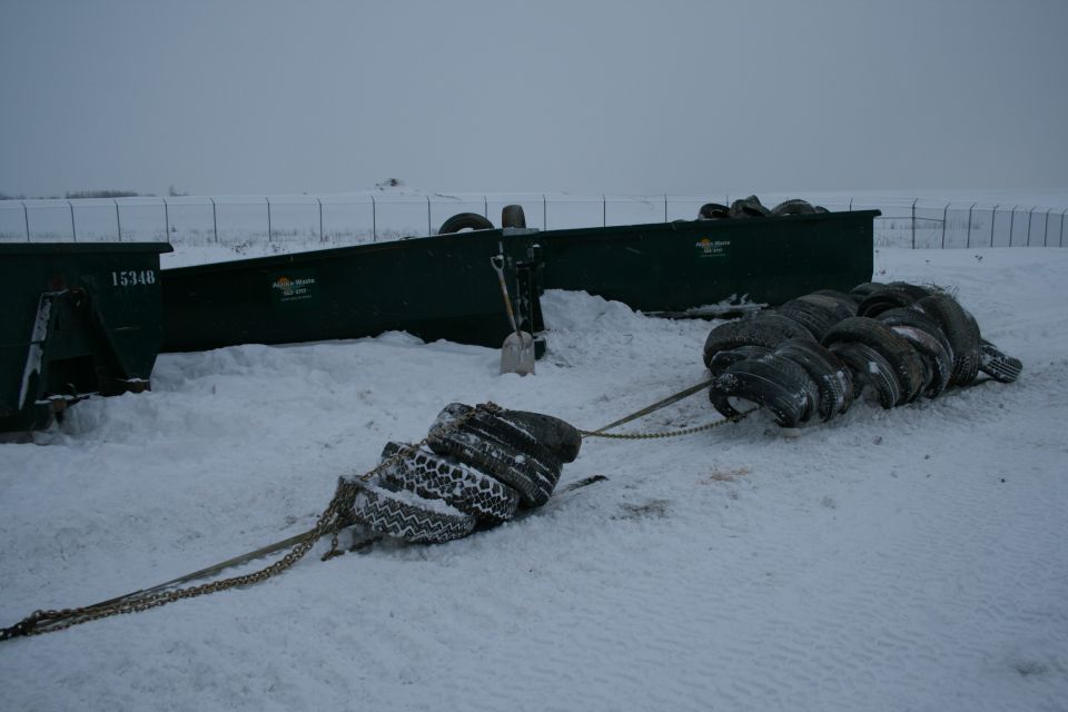 two dumpsters and a chain of tires in the snow