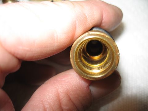 1968 Shelby GT500 - A close-up view of the threaded interior of a brass fitting, held by human fingers.