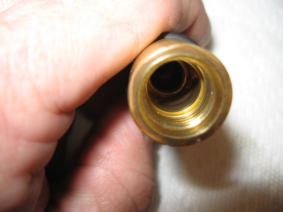 Close-up of a brass fitting with internal threads being held by fingers