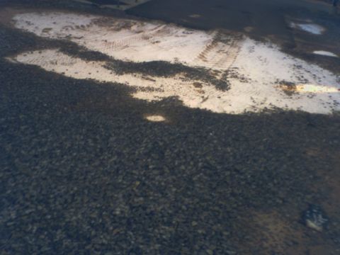 1987 Suzuki Samurai - Tire tracks are visible in a light-colored area amidst dark gravel.