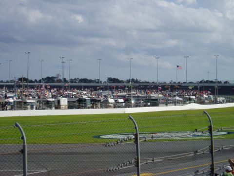2000 Ford E350 - A wide view of RV campers and spectators gathered at a race track, with a grassy infield and stadium seating in the background.