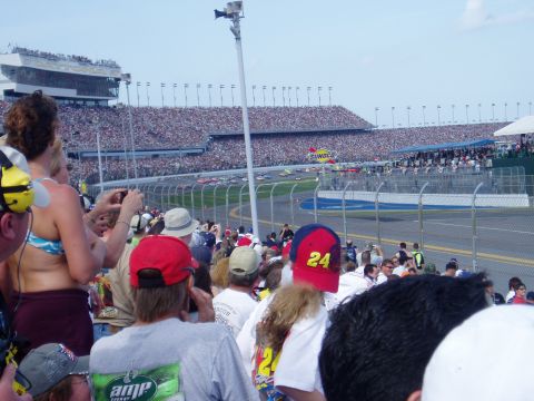 2000 Ford E350 - A large crowd watches a NASCAR race from the grandstands at a speedway.