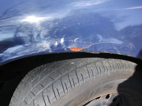 1999 Ford Crown Victoria - Rust is forming on the lower part of the blue car's fender, near the tire.