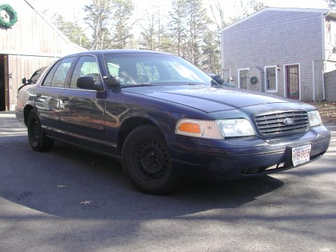 1999 Ford Crown Victoria - Dark blue Ford Crown Victoria sedan parked in front of a house and garage. The year is likely 1998 based on body style.