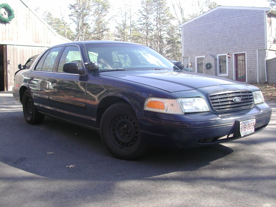 Dark blue Ford Crown Victoria sedan parked in driveway, front quarter view. License plate reads 618 027