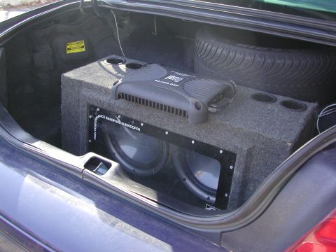 1999 Ford Crown Victoria - Car trunk interior with aftermarket audio equipment and spare tire.